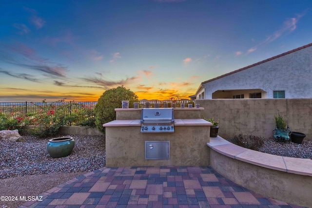 patio terrace at dusk with a grill and exterior kitchen