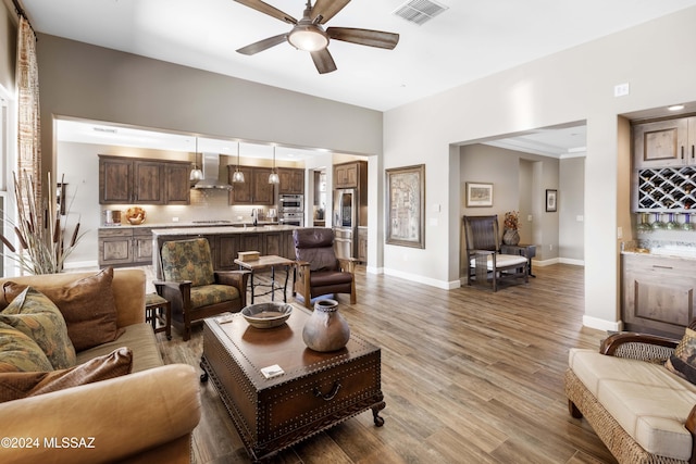 living room featuring ceiling fan, light hardwood / wood-style flooring, and sink