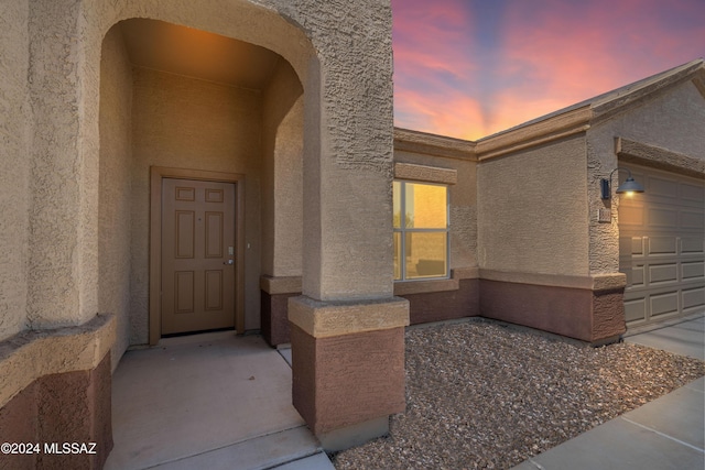 exterior entry at dusk featuring a garage