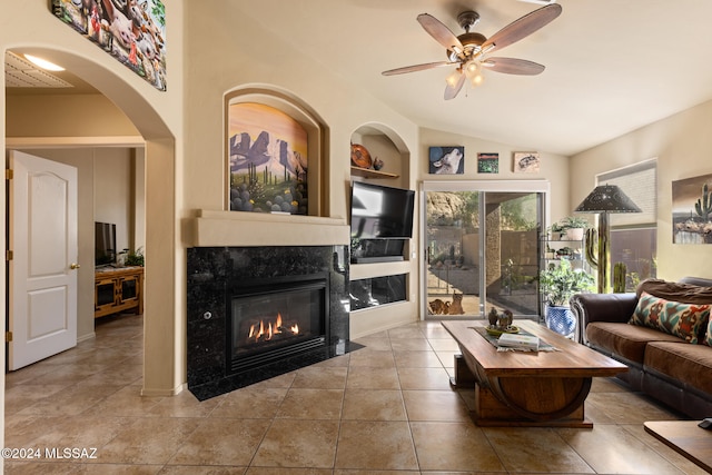 tiled living room with built in shelves, ceiling fan, a high end fireplace, and vaulted ceiling