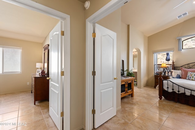 hallway with light tile patterned flooring and vaulted ceiling