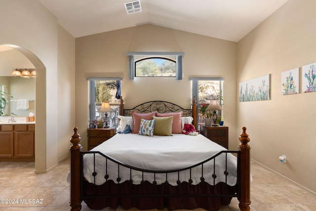 bedroom featuring ensuite bath, lofted ceiling, and sink