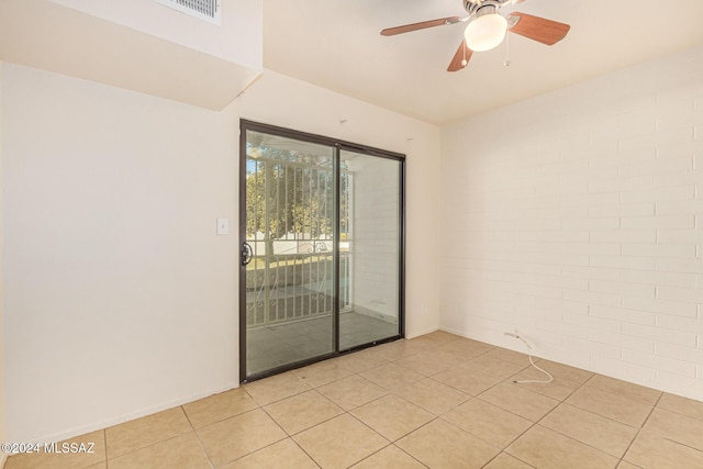 tiled empty room with ceiling fan and brick wall