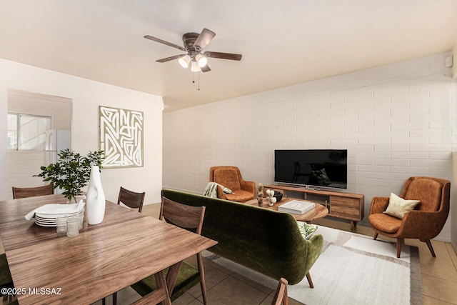 tiled living room with ceiling fan and brick wall