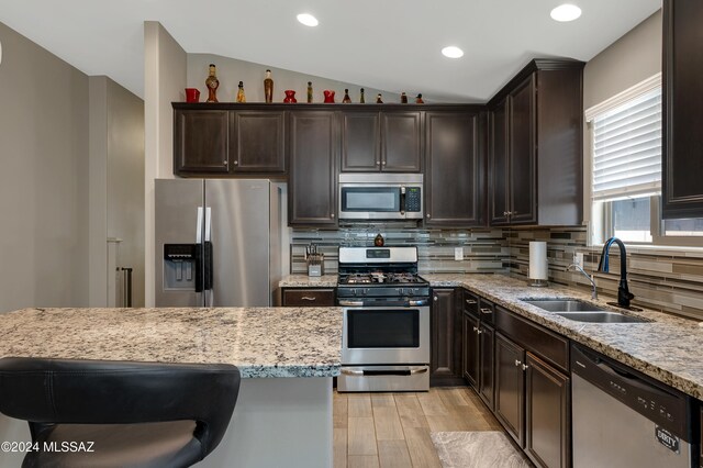 kitchen featuring sink, backsplash, vaulted ceiling, and appliances with stainless steel finishes