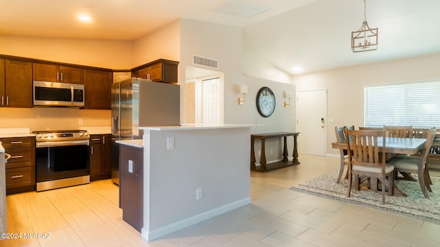 kitchen featuring lofted ceiling, appliances with stainless steel finishes, decorative light fixtures, a kitchen island, and dark brown cabinets