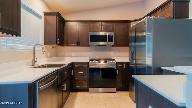 kitchen with dark brown cabinetry, stainless steel appliances, vaulted ceiling, and sink