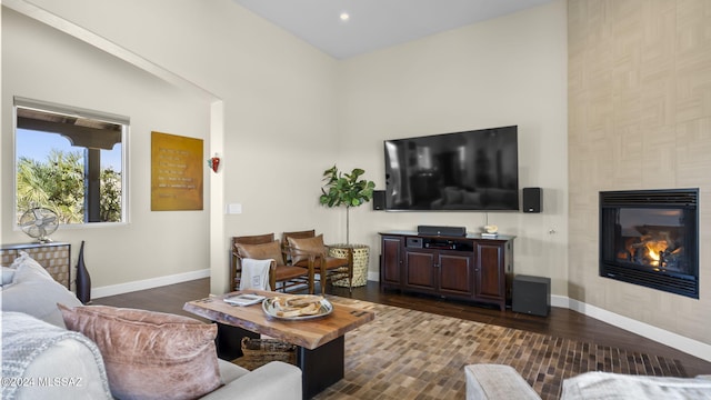 living room with vaulted ceiling, a tile fireplace, and dark hardwood / wood-style floors