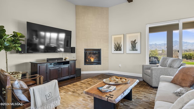 living room featuring a mountain view, a tiled fireplace, hardwood / wood-style floors, and a high ceiling