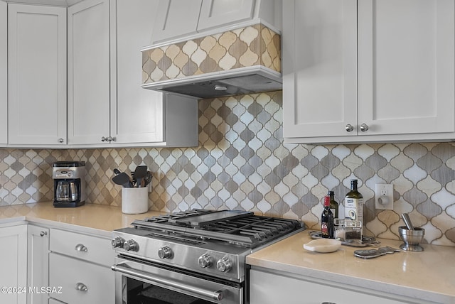 kitchen with white cabinetry, backsplash, and high end stove