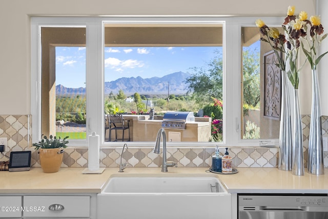 kitchen featuring a mountain view, stainless steel dishwasher, sink, and backsplash