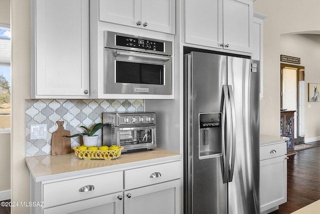 kitchen featuring dark wood-type flooring, appliances with stainless steel finishes, white cabinetry, and tasteful backsplash