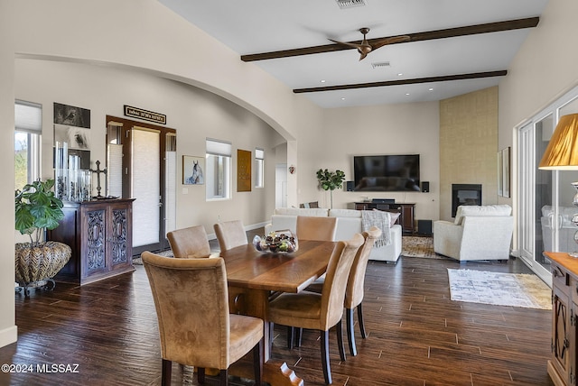 dining space with dark wood-type flooring, beam ceiling, a fireplace, and ceiling fan