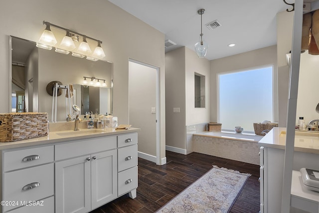 bathroom with vanity, a relaxing tiled tub, and hardwood / wood-style flooring