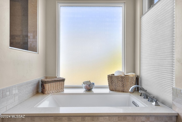 bathroom featuring a relaxing tiled tub and a wealth of natural light