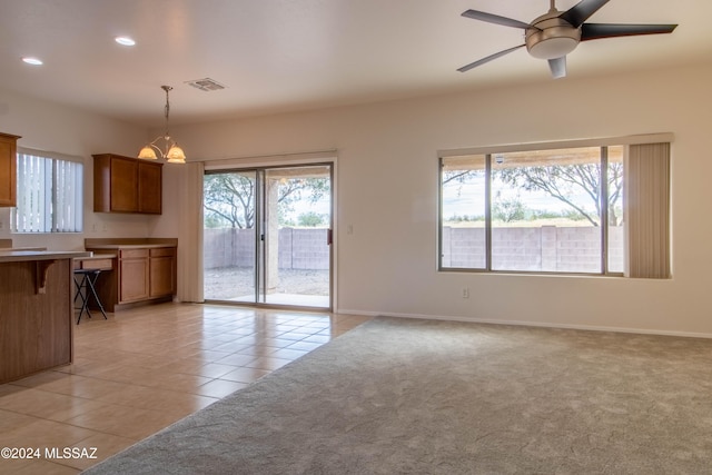 kitchen with ceiling fan with notable chandelier, a healthy amount of sunlight, light colored carpet, and hanging light fixtures