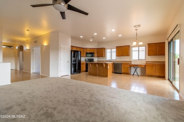 kitchen featuring decorative light fixtures, black appliances, a wealth of natural light, and a kitchen island