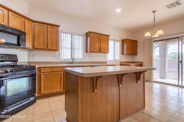 kitchen featuring a kitchen island, light tile patterned flooring, black appliances, pendant lighting, and sink