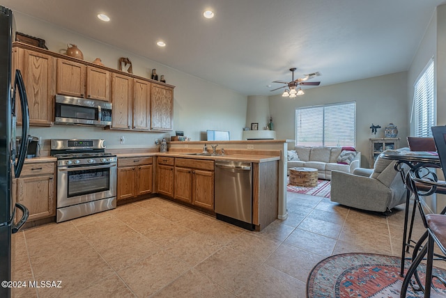 kitchen with sink, kitchen peninsula, stainless steel appliances, and ceiling fan