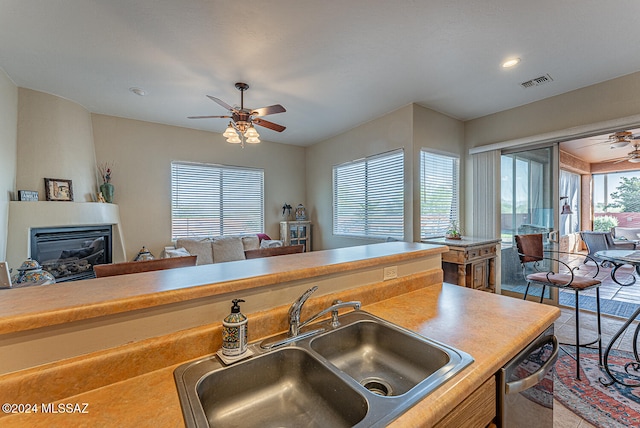 kitchen featuring dishwasher, sink, a fireplace, and ceiling fan