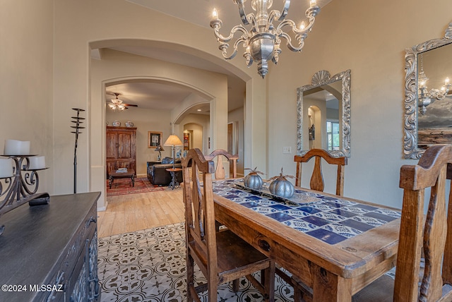 dining area featuring ceiling fan with notable chandelier and hardwood / wood-style floors