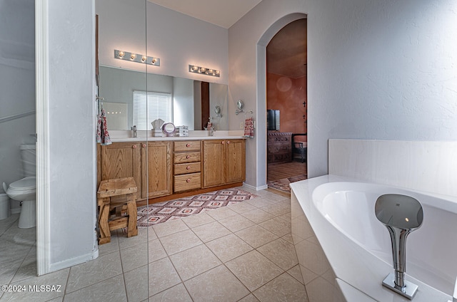 bathroom with toilet, a tub, vanity, and tile patterned flooring