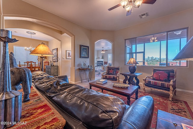 living room featuring a healthy amount of sunlight, wood-type flooring, and ceiling fan with notable chandelier