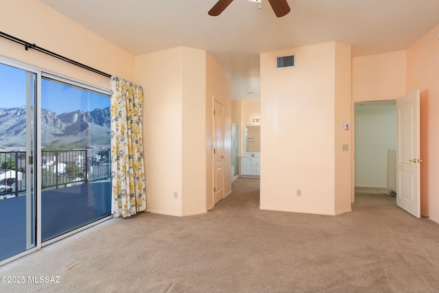 carpeted spare room with a mountain view and ceiling fan