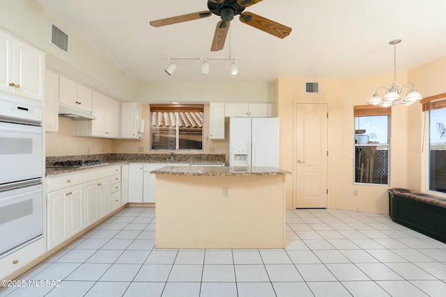 kitchen featuring white appliances, ceiling fan with notable chandelier, light tile patterned floors, white cabinets, and a center island