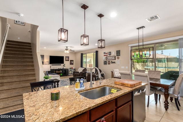 kitchen featuring ceiling fan, light stone countertops, sink, and decorative light fixtures