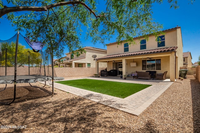 rear view of house with a patio area, outdoor lounge area, a trampoline, and ceiling fan