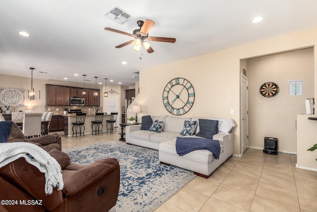 tiled living room featuring ceiling fan with notable chandelier