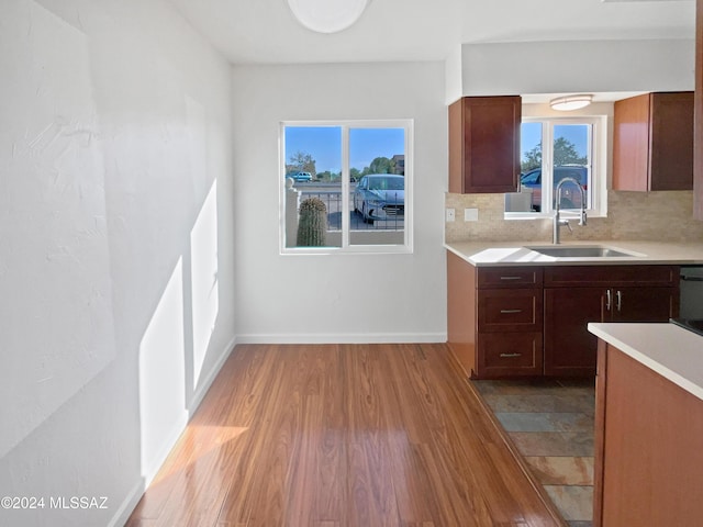 kitchen with a sink, light countertops, wood finished floors, and a healthy amount of sunlight