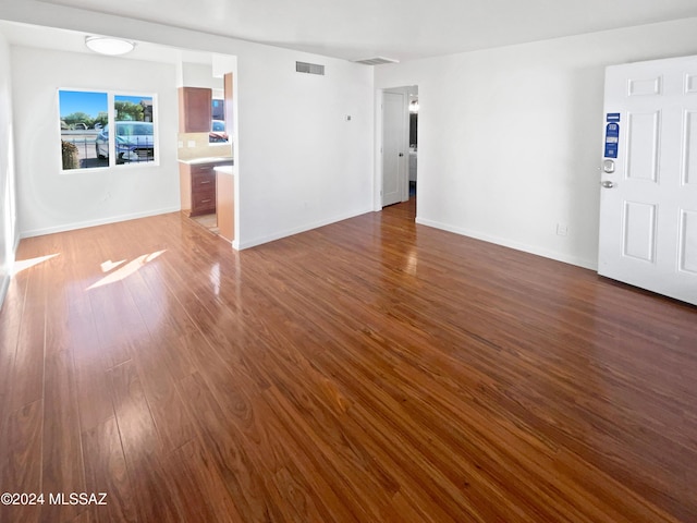 unfurnished living room featuring visible vents, dark wood finished floors, and baseboards