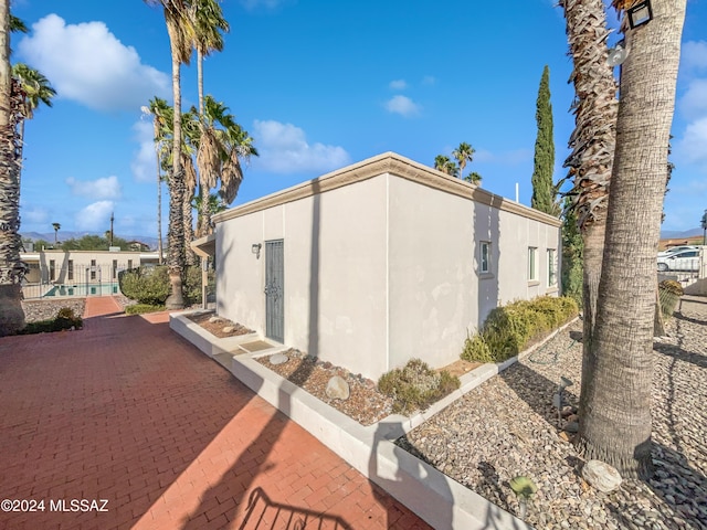 view of side of property with fence and stucco siding
