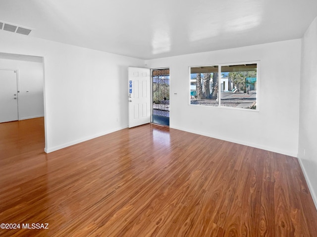 spare room featuring baseboards, visible vents, and wood finished floors