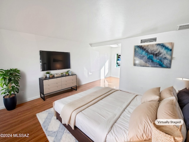 bedroom featuring baseboards, wood finished floors, and visible vents