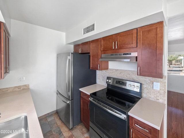 kitchen with visible vents, light countertops, under cabinet range hood, tasteful backsplash, and appliances with stainless steel finishes