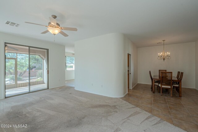 interior space featuring carpet flooring and ceiling fan with notable chandelier