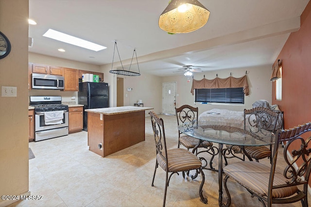 kitchen with ceiling fan, stainless steel appliances, a skylight, and a kitchen island