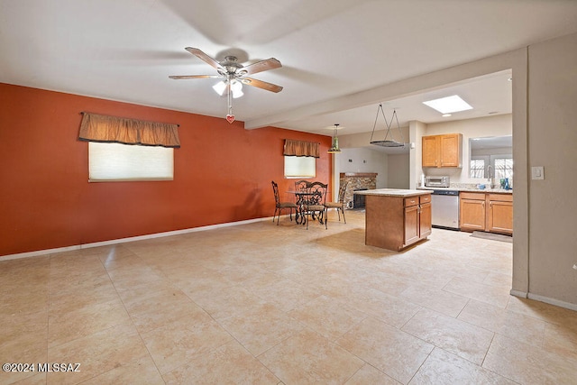 kitchen with beamed ceiling, hanging light fixtures, stainless steel appliances, a center island, and ceiling fan