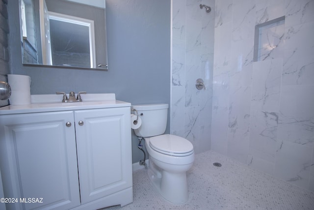 bathroom featuring a tile shower, tile patterned floors, vanity, and toilet