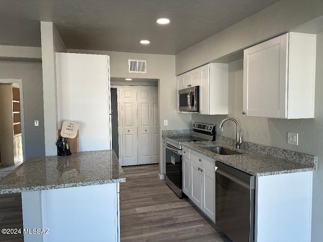 kitchen with white cabinets, appliances with stainless steel finishes, stone countertops, and sink