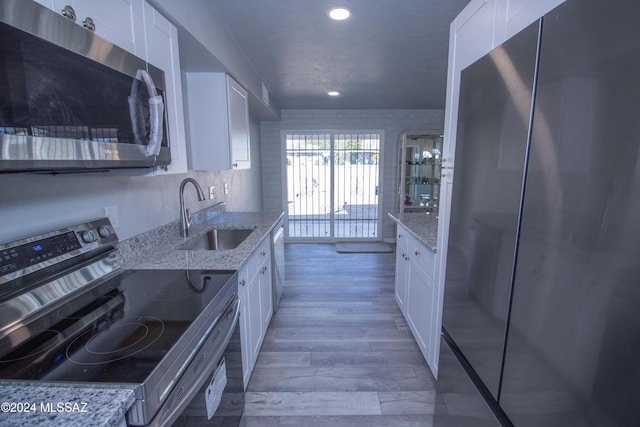 kitchen featuring light stone countertops, sink, white cabinets, and appliances with stainless steel finishes