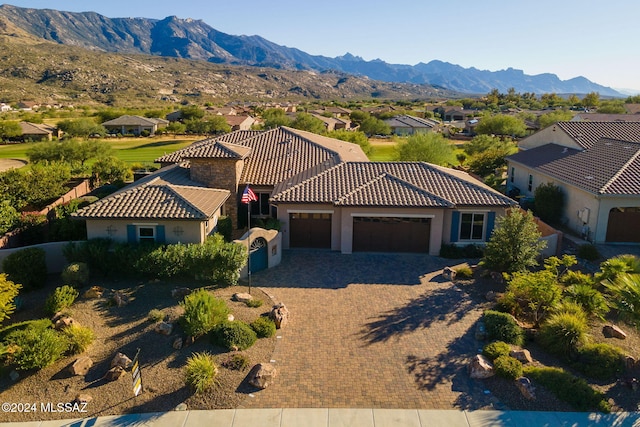 view of front of house with decorative driveway, a mountain view, a garage, a residential view, and a tiled roof