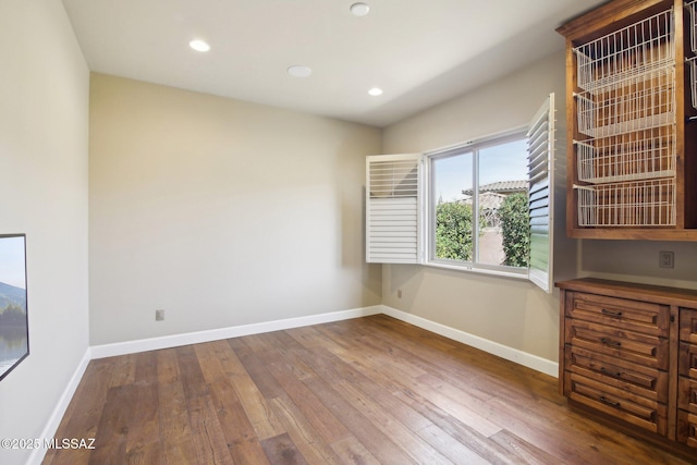 spare room with recessed lighting, wood finished floors, and baseboards