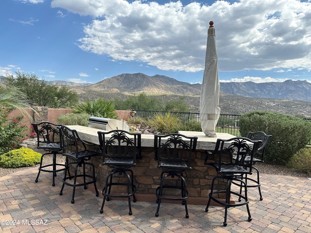 view of patio / terrace featuring outdoor dry bar, fence, and a mountain view