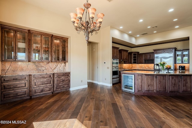 kitchen with wine cooler, decorative light fixtures, appliances with stainless steel finishes, glass insert cabinets, and dark brown cabinets