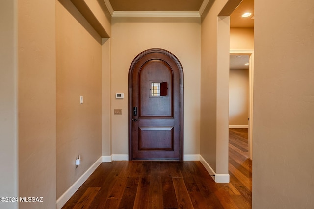 foyer with dark wood-style floors, baseboards, arched walkways, and crown molding