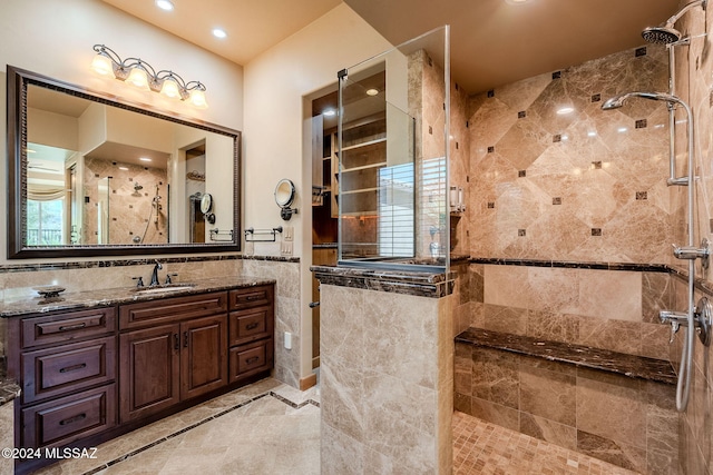 bathroom with a tile shower, tile walls, and vanity